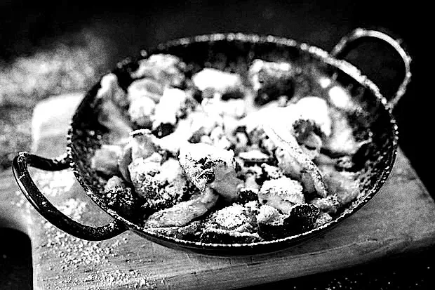 Kaiserschmarrn mit Puderzucker in einer Eisenpfanne, schwarz-weiß