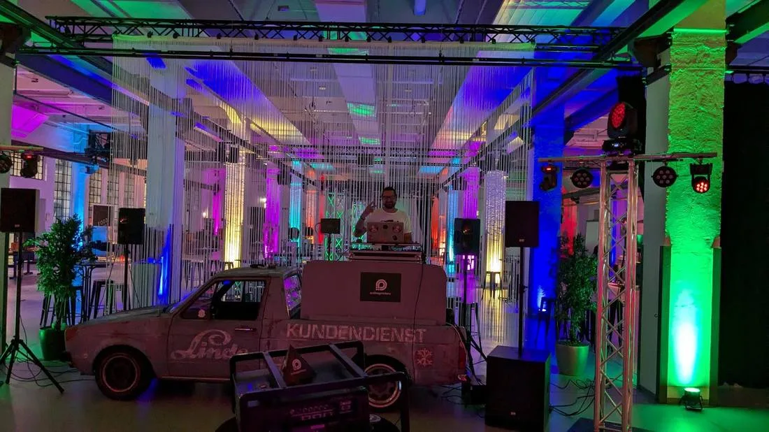 Halle mit farbigem Lichtdesign, in der Mitte der DJ-Caddy