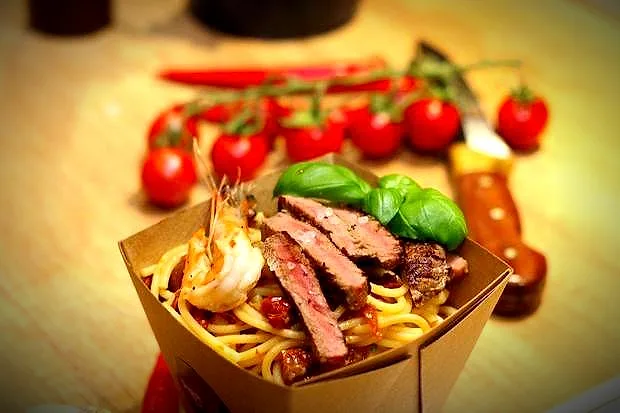 Pasta mit Garnele und Rinderhüfte in einer Papierbox